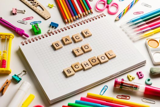 School office supplies and opened notebook on a desk with Back to school text made with wooden blocks