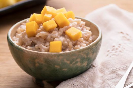 Delicious rice pudding in bowl topped with fresh mango.