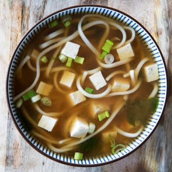 Red miso soup with tofu, green onions and udon noodles. Square orientation, close-up flat lay.