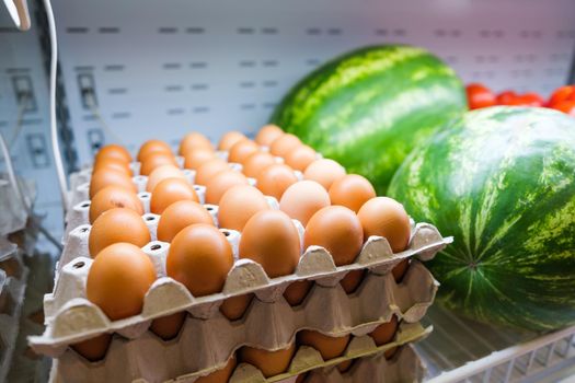 Healthy fruit and vegetables in grocery shop. Close up of basket with eggs in refrigerator.