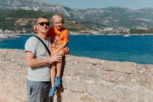 Cute family are having fun on the beach. Father and child against the background of the blue sea and sky. Travel, active lifestyle, vacation, rest concept. a man with a child on the shore. tourists on the shore of Budva, Montenegro.