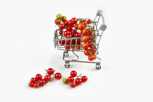 Mini shopping cart full with cherry tomatos on white background. Copy space