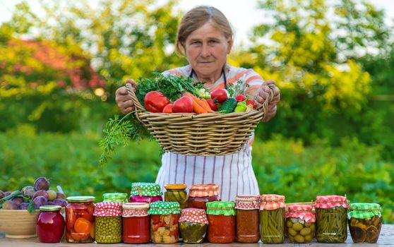 Senior woman preserving vegetables in jars. Selective focus. Food.