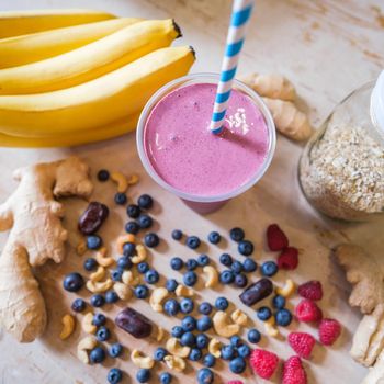 Healthy fruit shake on table with fruits and vegetables ingredients around.