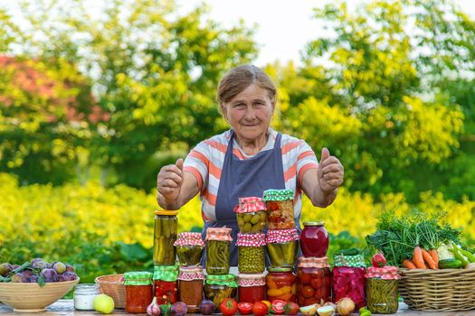 Senior woman preserving vegetables in jars. Selective focus. Food.