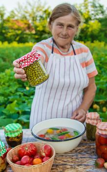 Senior woman preserving vegetables in jars. Selective focus. Food.