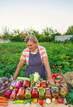 Senior woman preserving vegetables in jars. Selective focus. Food.