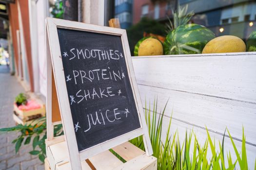 Vegetables and fruit store window with advert on board.