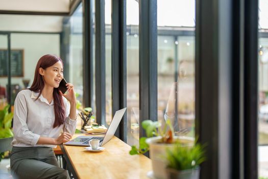 Asian businesswoman using the phone to contact a business partner.