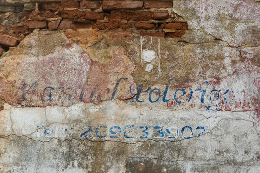 Erased handwritten inscription over the entrance to the ruined building close up background