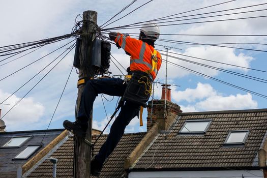 Telecommunication engineer performing maintenance at the top of a telephone pole.