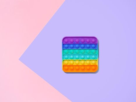 Popit or simple dimple toy on purple and pink background with copy space. Popular silicone colorful antistress pop it toy for child. Top view from above