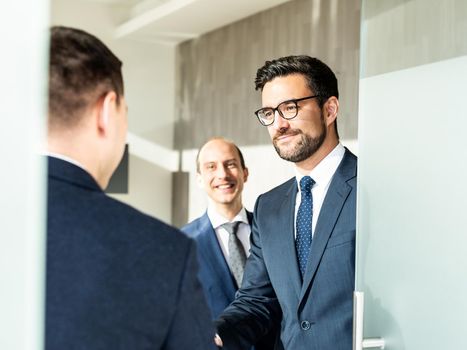 Group of confident business people greeting with a handshake at business meeting in modern office. Closing the deal agreement by shaking hands. Business and entrepreneurship success concept.