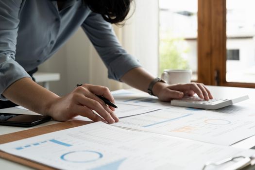 accountant working on desk using calculator for calculate finance report in office