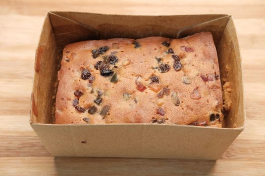 slice of bakery fruit cake in a paper packet on table ,