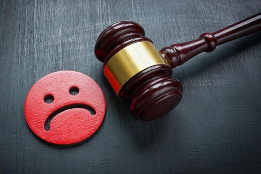 Unhappy smiley and a gavel. Discrimination and Bullying law concept.