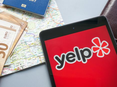 KYIV, UKRAINE - July 21, 2022. Yelp Inc logo near a map and money. Editorial.