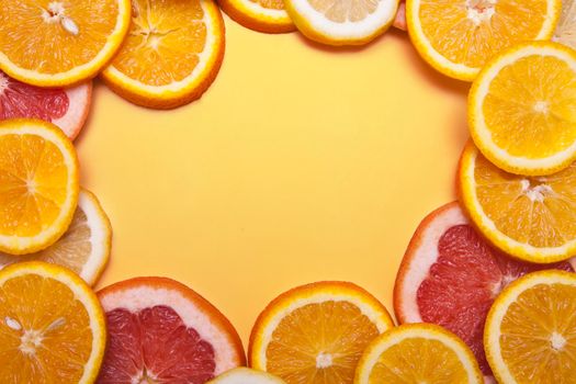 Flat lay slices of fresh orange, grapefruit and lemon formed a frame on a orange background. Bright summer concept with copy space.