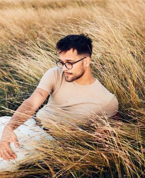 Portrait of a young man fashion model outdoors in the field