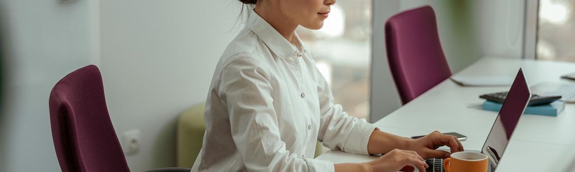 Pretty asian business woman working laptop sitting in modern office. High quality photo