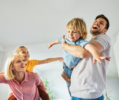 Familyof four father, mather, daughter and son having fun playing at home