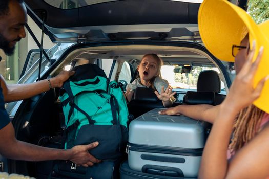 Small kid and mixed people going on vacation, loading travel bags in vehicle trunk. Leaving on holiday adventure with family and friends, putting suitcase or trolley in automobile before roadtrip.