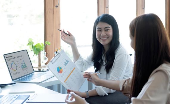 Two young Asian businesswoman discuss investment project working and planning strategy. Business people talking together with laptop computer at office..