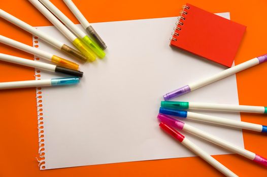 Creative kids, concept. Colorful crayon paints and blank notepad on orange color background, red little notepad. Empty paper for painting, space, template. Education, Back to School concept.