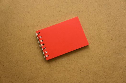 Red notepad for notes with red sheets. Blank space for notes. Mocap. On gray warm ochre kraft background. Holiday calendar notes on notepad. Background for inscriptions. Small notepad with a spring
