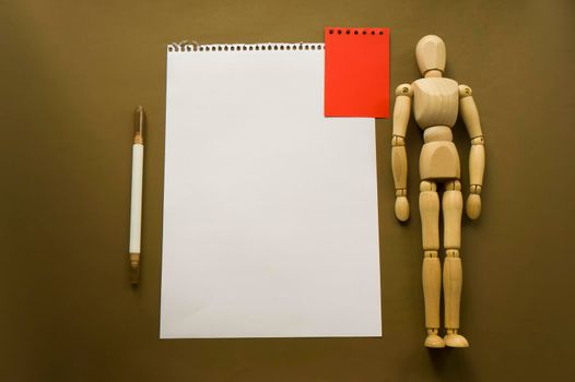 Wooden doll and a blank piece of paper. Wooden mannequin with sheets of paper concept, blank space. Creativity and art