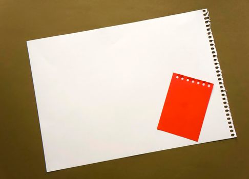 Blank sheet of paper space for design and lettering on a beautiful craft background red notepad sheet. Perforated sheet torn from notepad obliquely lying on the surface. Square sheet of paper copyspace