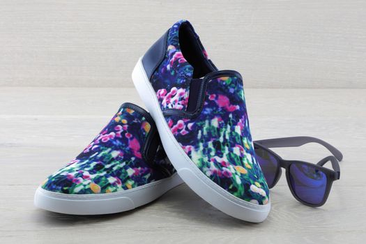 A pair of colourful pumps on wood background with sunglasses