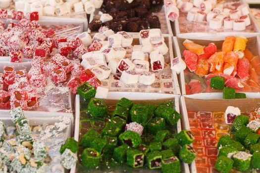 Traditional oriental sweet pastry cookies, nuts, dried fruits, pastilles, marmalade, Turkish desert with sugar, honey and pistachio, in display at a street food market