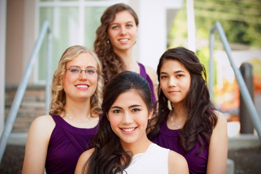 Beautiful biracial young bride smiling with her multiethnic group of bridesmaids in purple dresses