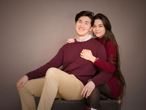 Attractive young biracial couple in burgundy colored sweaters posing  for portrait