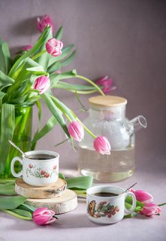 Still life, concept of early spring breakfast with coffee or tea and cupcake on the background of a bouquet of tulips and daffodils