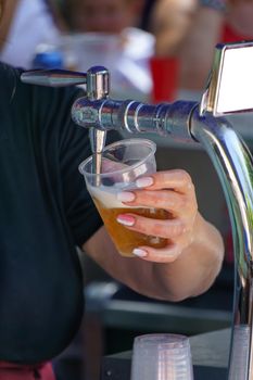 close-up of a woman with painted fingernails serving a draught beer with foam