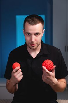 Portrait of a smiling young man holding stress balls, massage therapist.