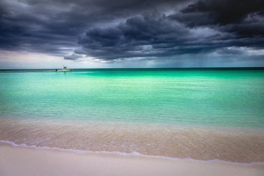 Dramatic sky with storm clouds over caribbean beach with motorboat, Negril Seven Mile Beach, Jamaica
