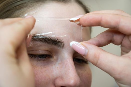 The master uses a plastic film during lamination of the eyebrows