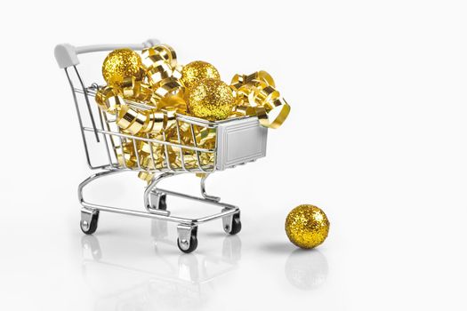 Full of Christmas decoration balls in miniature shopping cart as Christmas and new year season spending concept. White background. Copy space