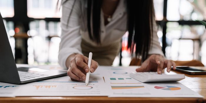 Woman accountant using calculator and laptop computer in office, businessman working at home, finance and accounting concept