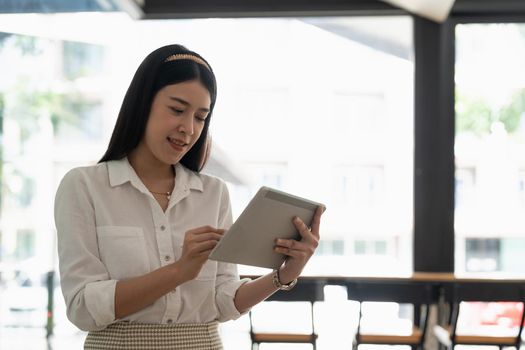 Young asian girl using digital tablet stand at home office.