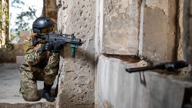 A woman in an army uniform shoots a firearm in an abandoned building