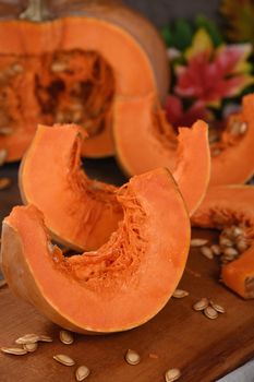 Whole fresh orange big pumpkin and slice of pumpkin on wooden board, closeup. Organic vegetable product, ingredients for cooking, healthy food vegan