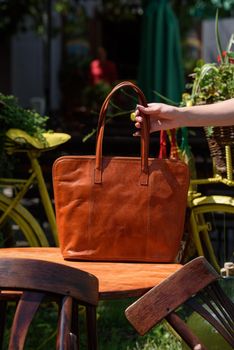 close-up photo of orange leather bag on a wooden table. outdoors photo