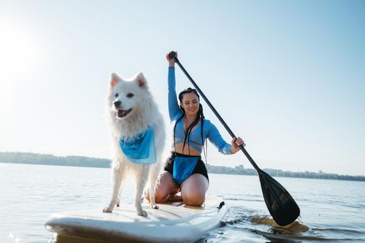 Cheerful Woman Paddleboarding with Her Pet on City Lake, Snow-White Japanese Spitz Dog Standing on Sup Board