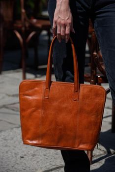 close-up photo of orange leather bag in a woman's handoutdoors photo