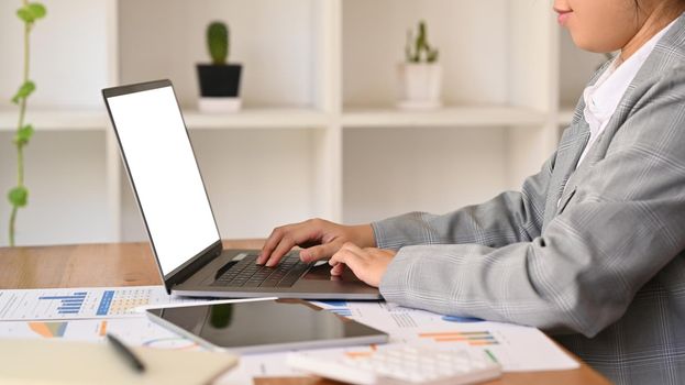 Side view female investor or economist working with digital tablet and financial document at office.