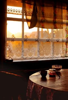 Dining room of veranda in summer house in sunset, country home of countryside in golden hour, cozy still life of rustic mood with light backlight from window and dark shadows of twilight